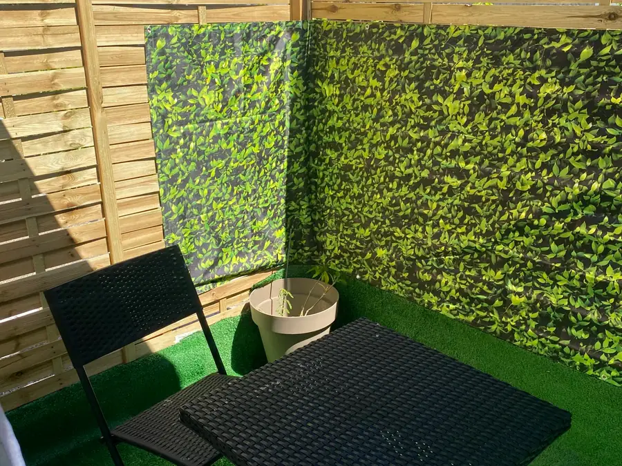 Terrasse privative avec table, chaises et mur végétal